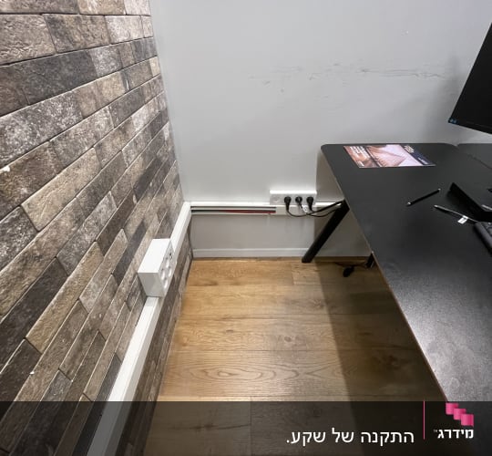 שקעי חשמל על קיר ליד שולחן עבודה